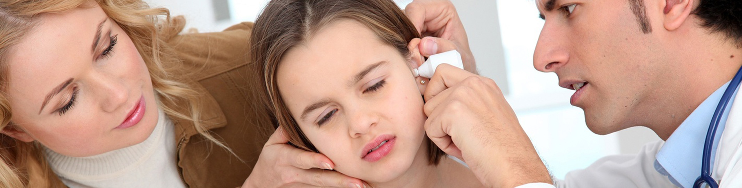 Ein Mädchen wird wegen einer Ohrenentzündung von einem Arzt untersucht.