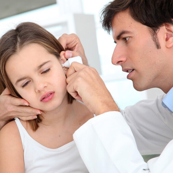 Ein Mädchen wird wegen einer Ohrenentzündung von einem Arzt untersucht.