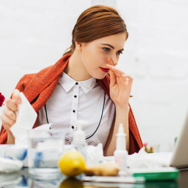 Kranke Frau mit Erkältung im Büro.