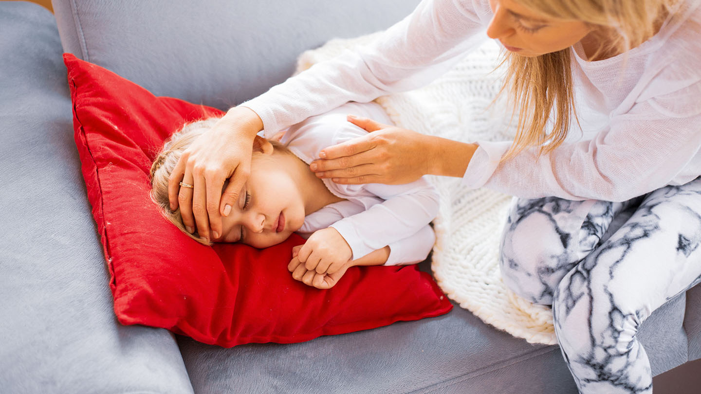 Eine Mutter misst die Temperatur ihres kranken Kindes.