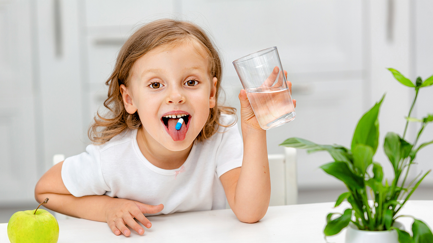 Das Mädchen nimmt ein Nahrungsergänzungsmittel zur Stärkung ihres Immunsystems.