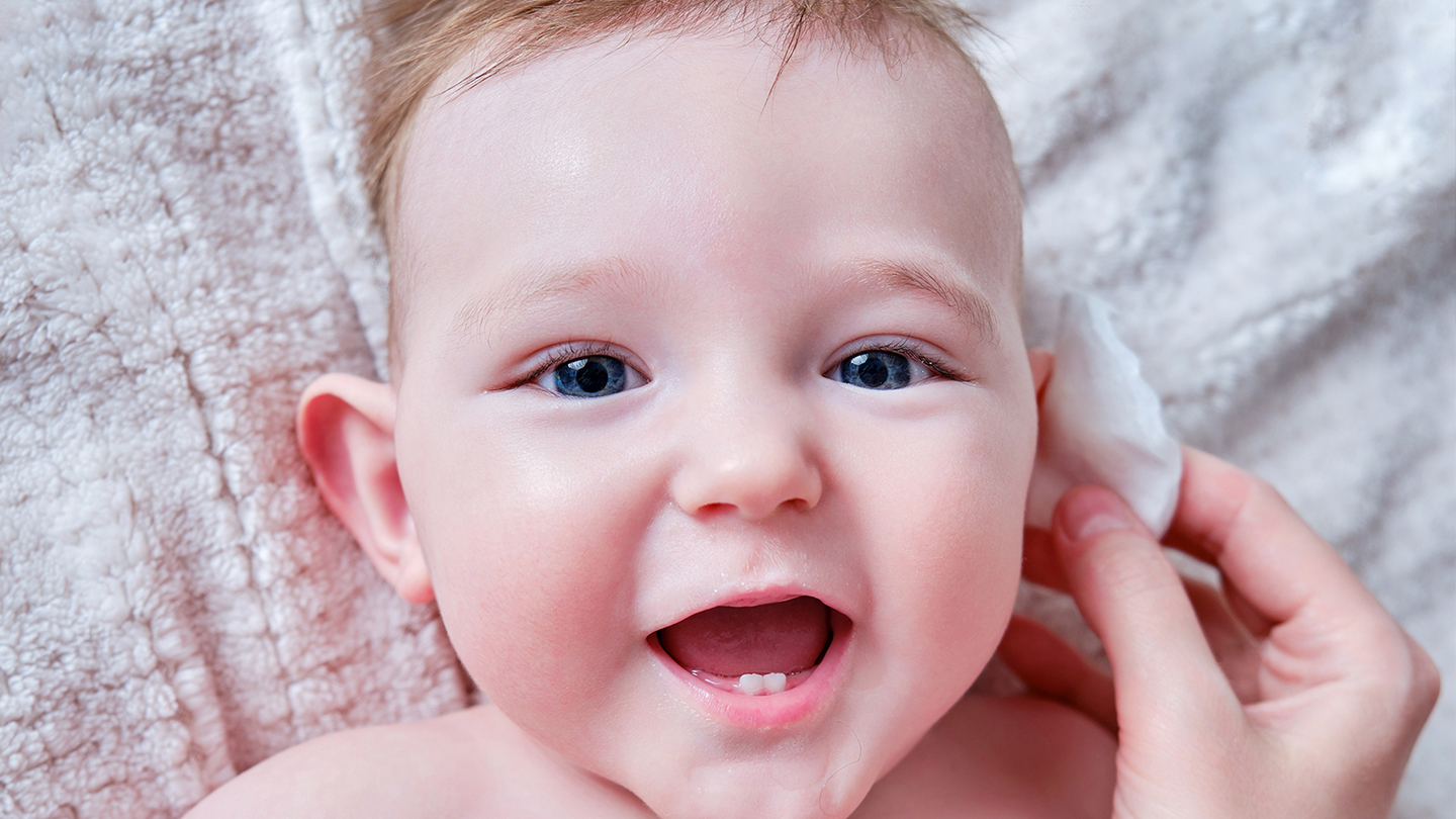 Ein Baby mit einer Ohrenentzündung auf einer Decke.
