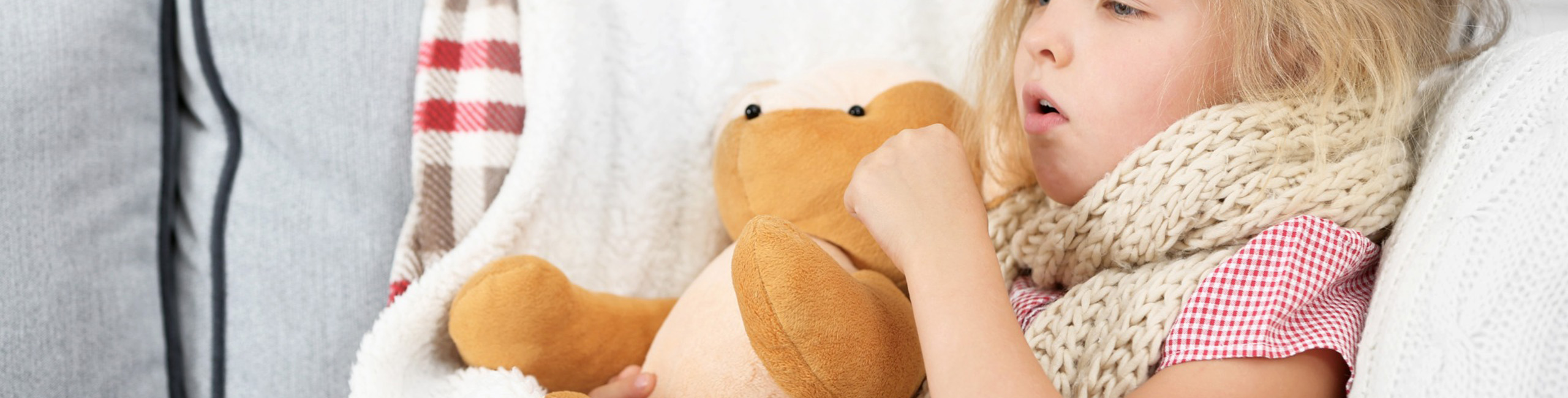 Ein krankes kleines Mädchen klammert sich an ein Stofftier.