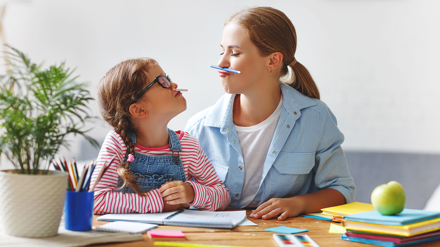 Die Schwestern spielen, während sie ihre Hausaufgaben machen.