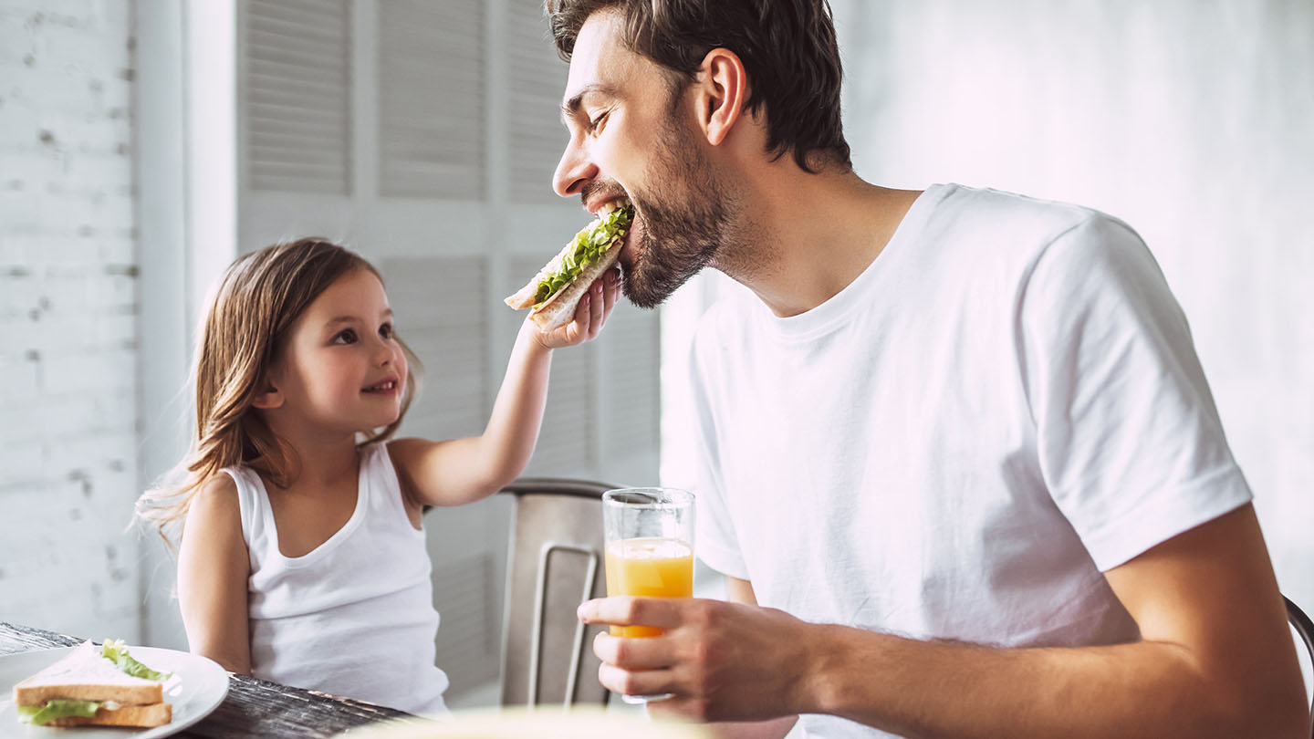 Vater und Kind genießen ein Sandwich.