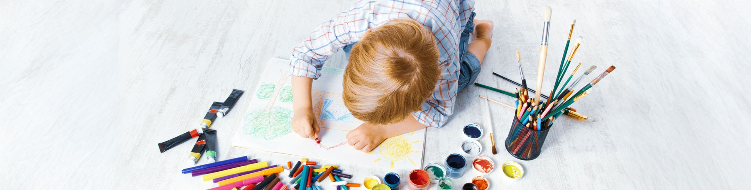 Ein Kind spielt mit Buntstiften auf dem Boden.