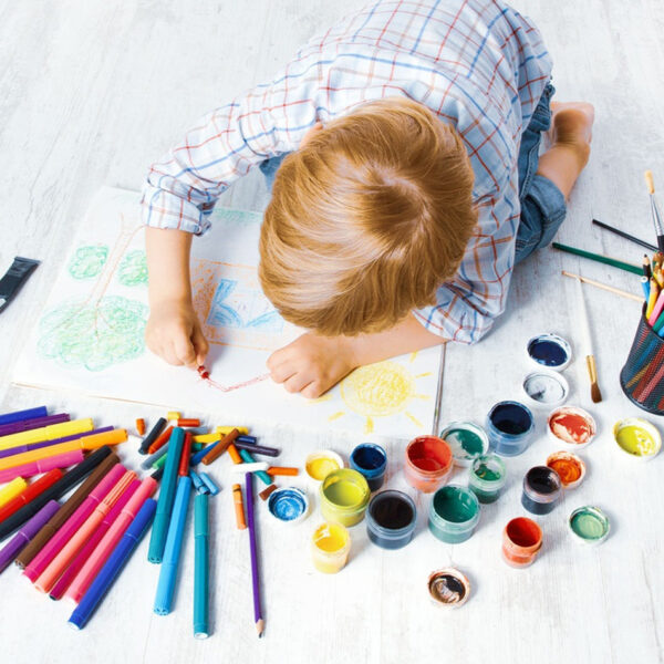 Ein Kind spielt mit Buntstiften auf dem Boden.