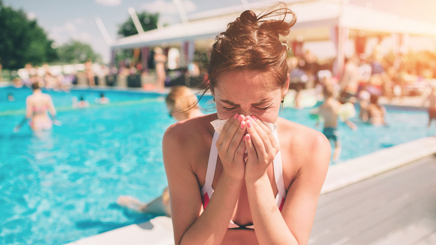Frau mit Erkältung am Pool, Sommer.