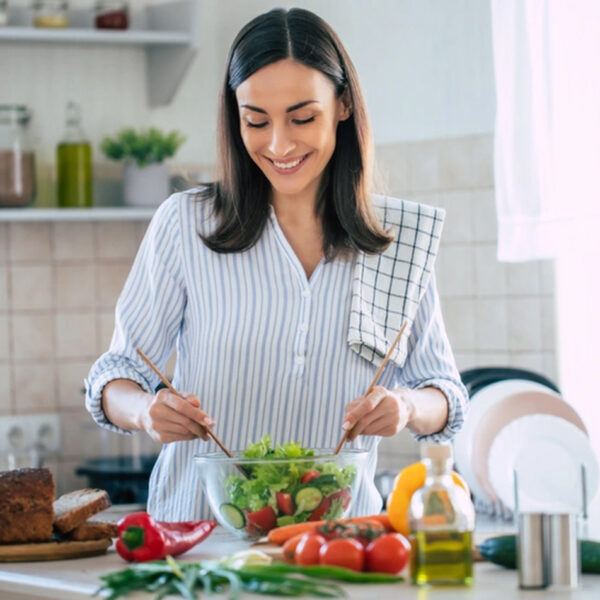 Eine Frau bereitet einen gesunden Salat voller Vitamin C und Zink zu.